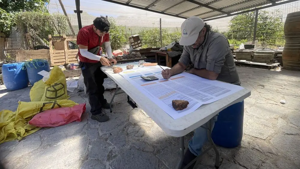 Dos geólogos describiendo muestras y completando planillas de logueo sobre una mesa de trabajo