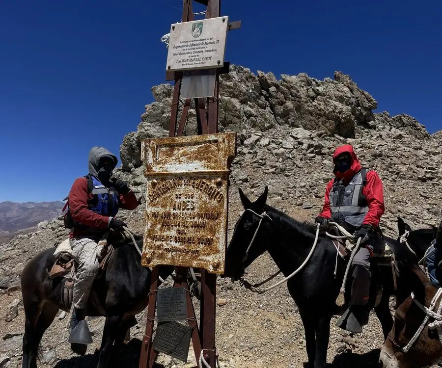 Dos integrantes del equipo montados en mulas en la cumbre del paso de Guana, en el límite entre Chile y Argentina