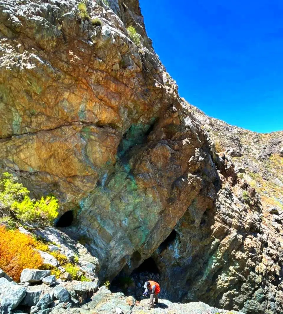 Afloramiento con mineralización de cobre y labores mineras antiguas, con un integrante del equipo al pie del farellón para dar escala