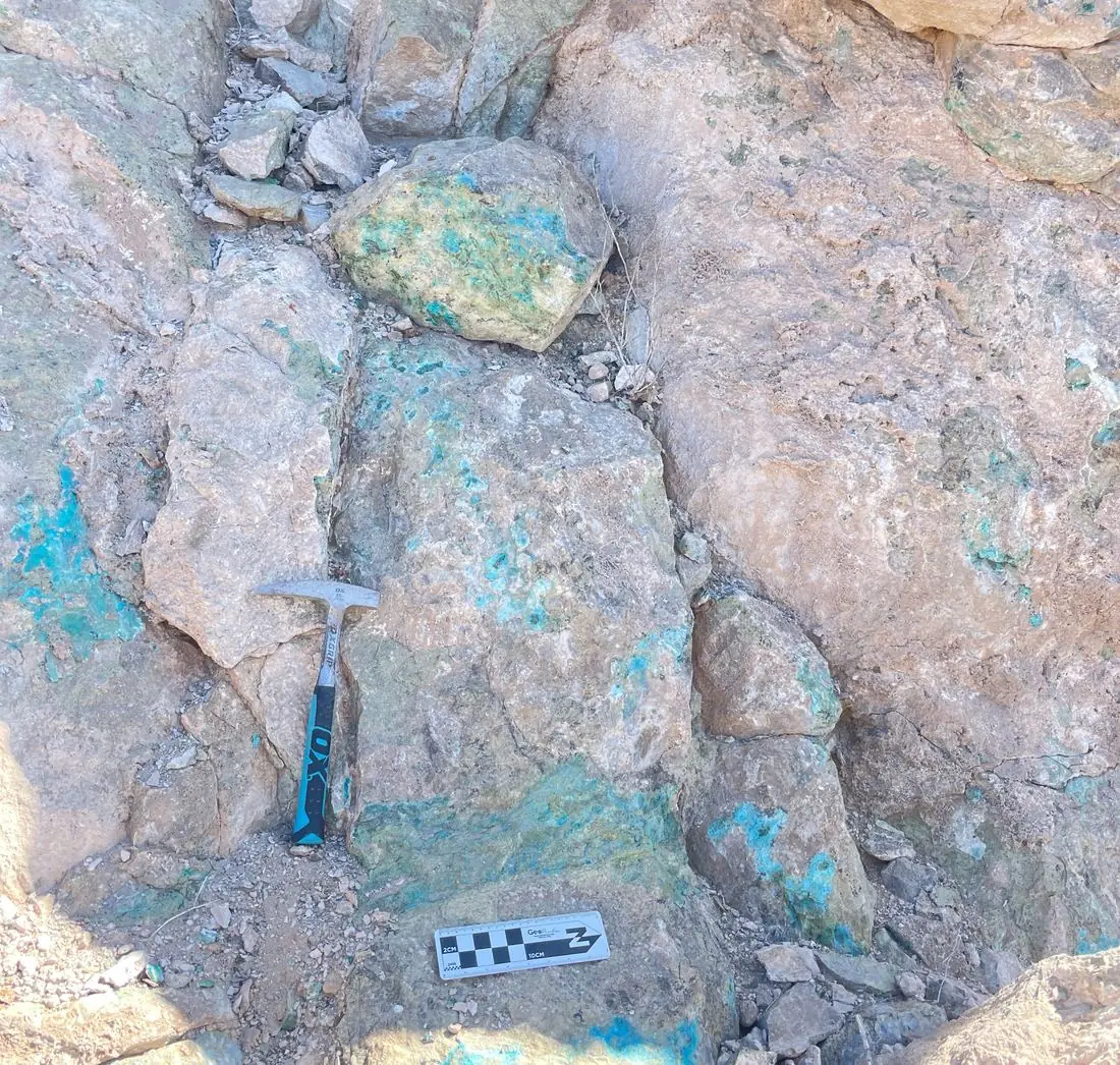 Óxidos de cobre en un afloramiento del proyecto Rama, con martillo de geólogo y escala gráfica como referencia
